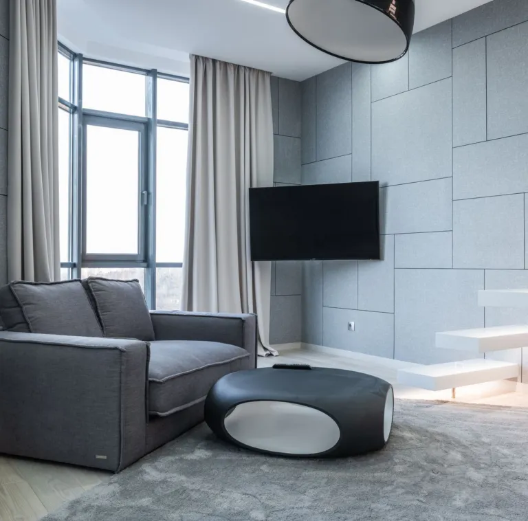Telewizor na ścianie w nowoczesnym salonie z szarą sofą
