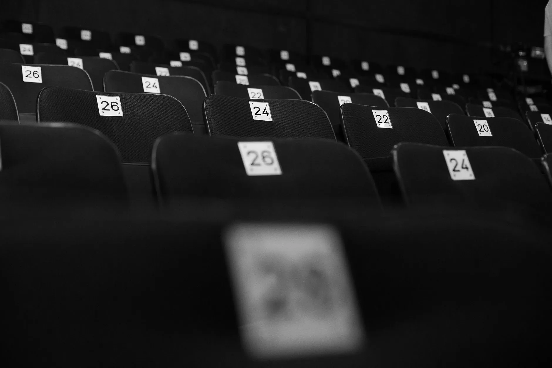 Puste ponumerowane fotele w ciemnej sali teatralnej