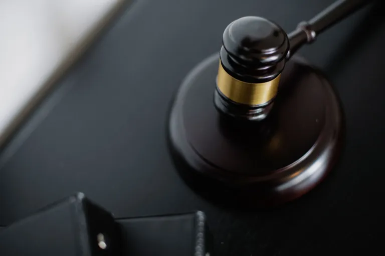 Drewniany młotek sędziowski leżący obok akt na stole