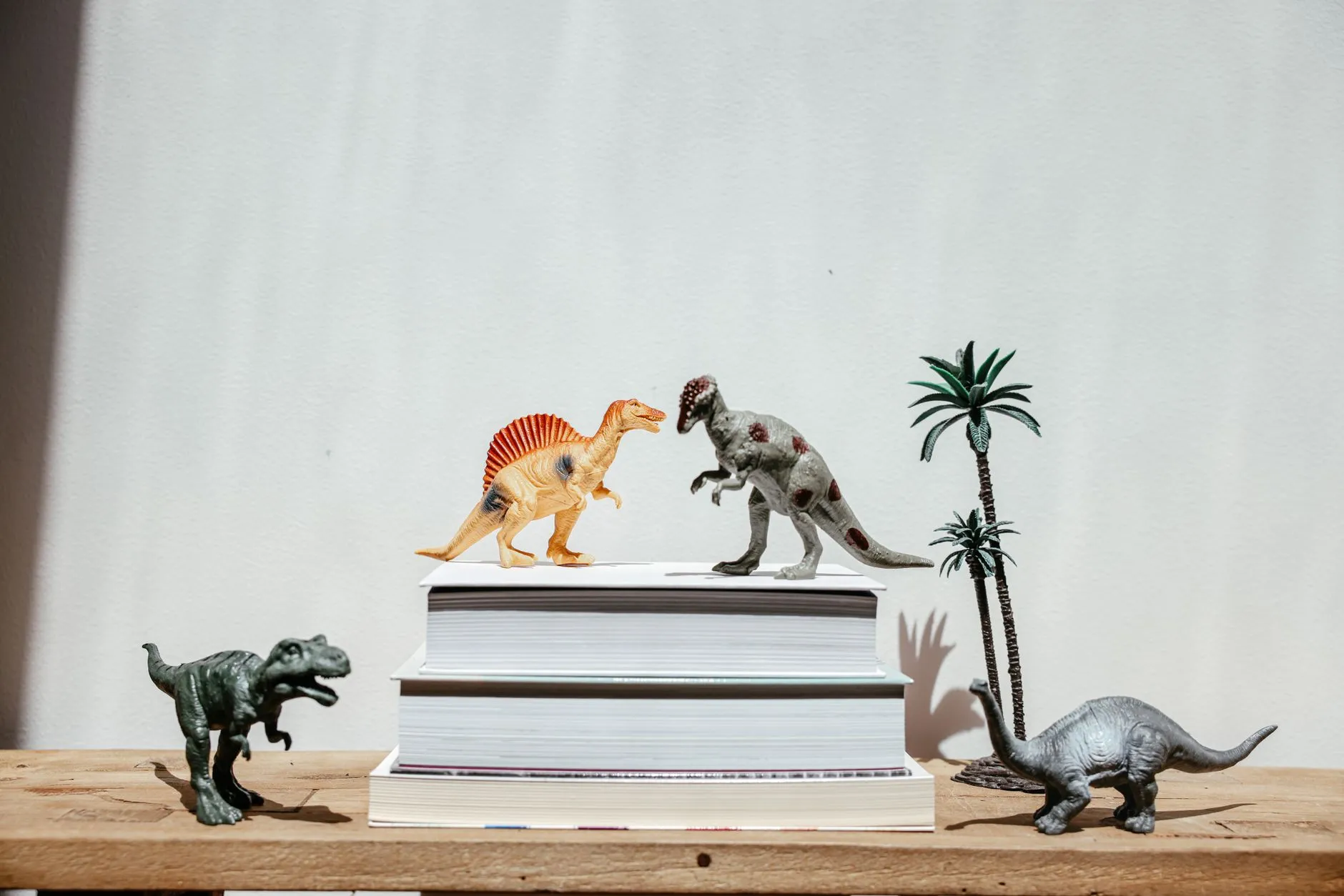 Figurki dinozaurów ustawione na stosach książek