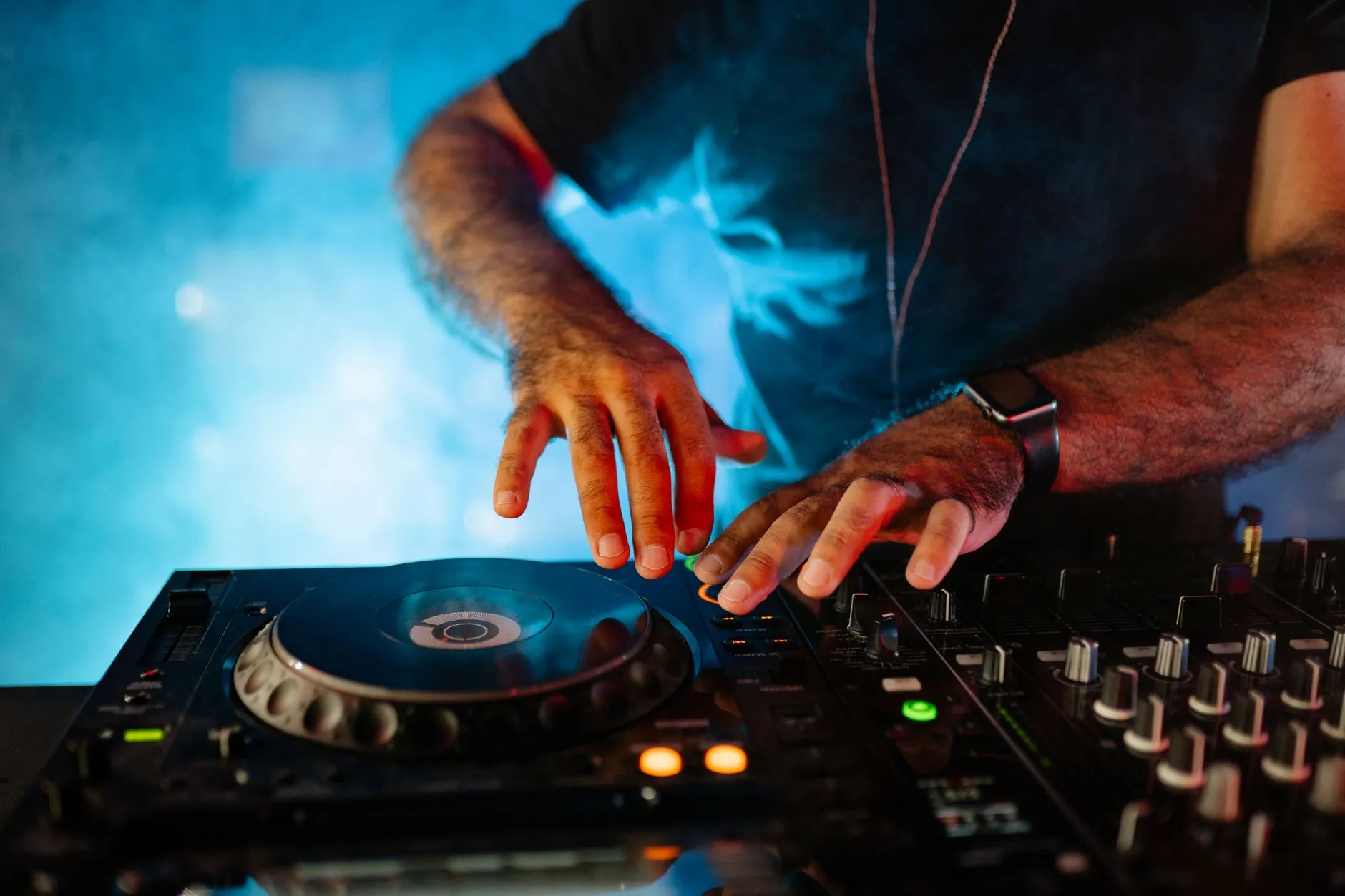 Dłonie DJ-a podczas miksowania muzyki na profesjonalnym sprzęcie