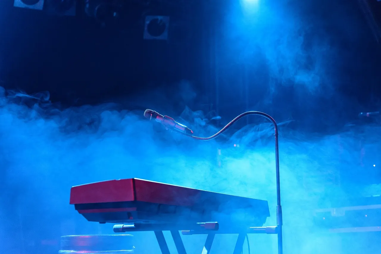 Pusta scena z mikrofonem, keyboardem i niebieskim oświetleniem