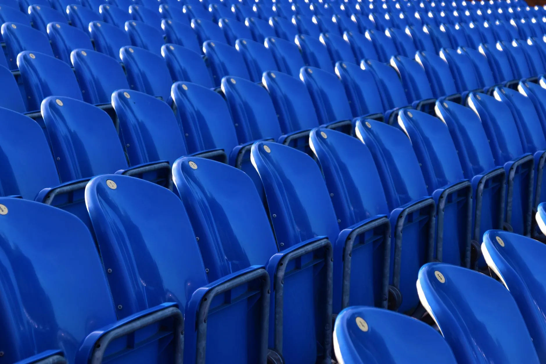 Puste niebieskie krzesełka na trybunach stadionu